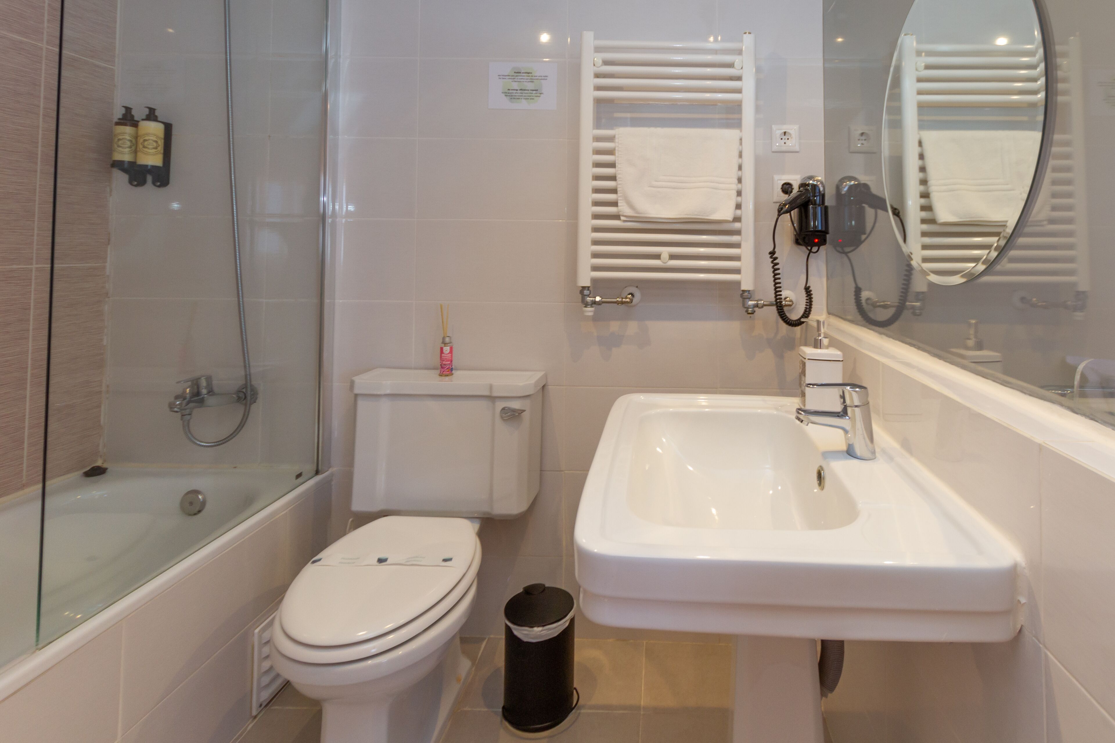 A modern bathroom with a glass-enclosed shower, a white toilet, a sink, and a mirror.