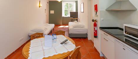 A compact hotel room with a dining area, kitchenette, and a bed.