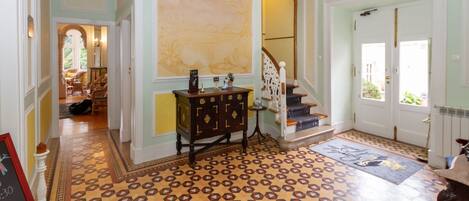Un pasillo con suelo estampado, una escalera y una puerta que da a otra habitación.