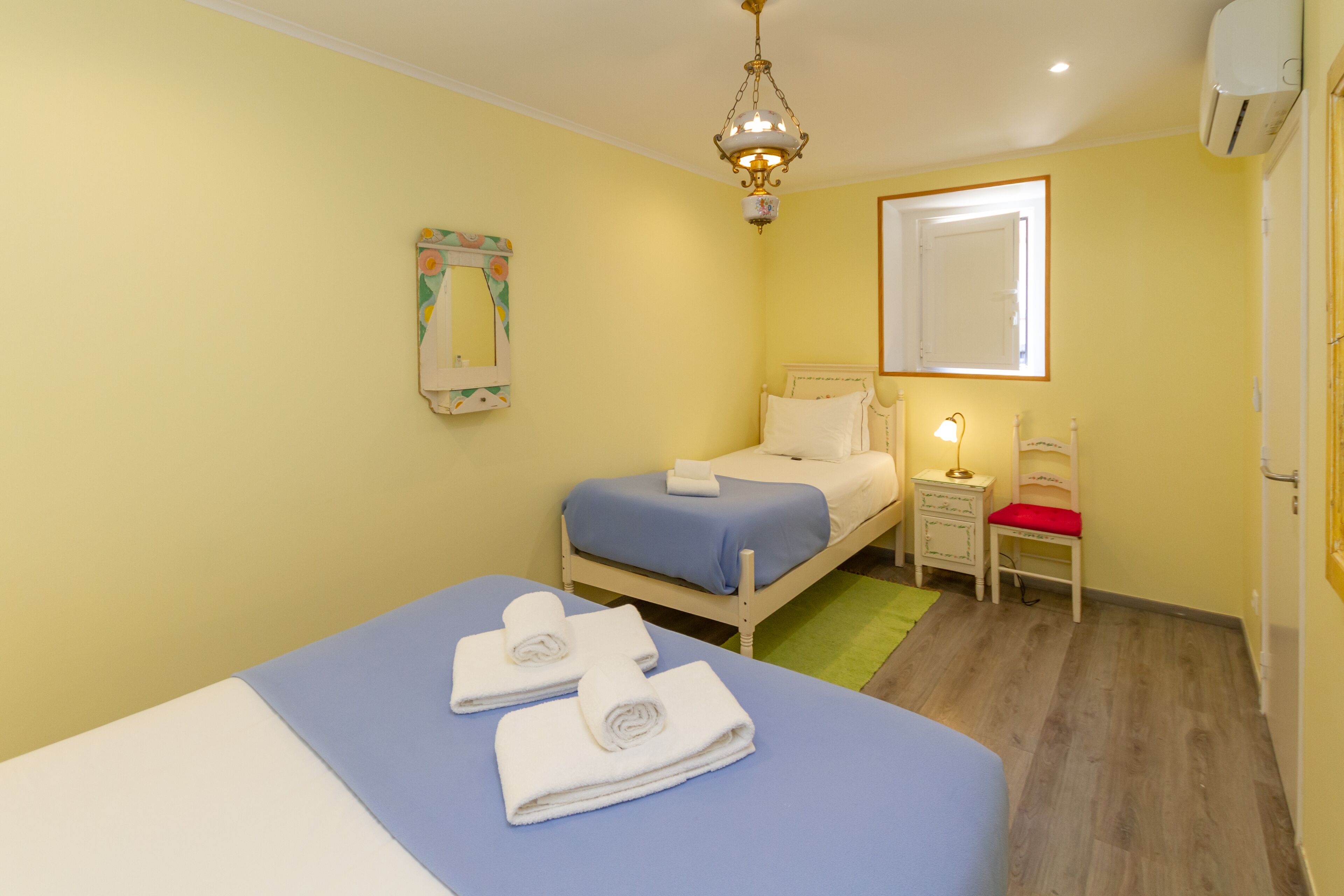 Ein Schlafzimmer mit Bett, Nachttisch, Sessel und einer Pendelleuchte.