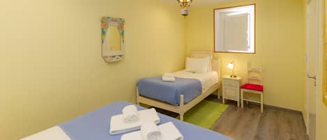 Ein Schlafzimmer mit Bett, Nachttisch, Sessel und einer Pendelleuchte.