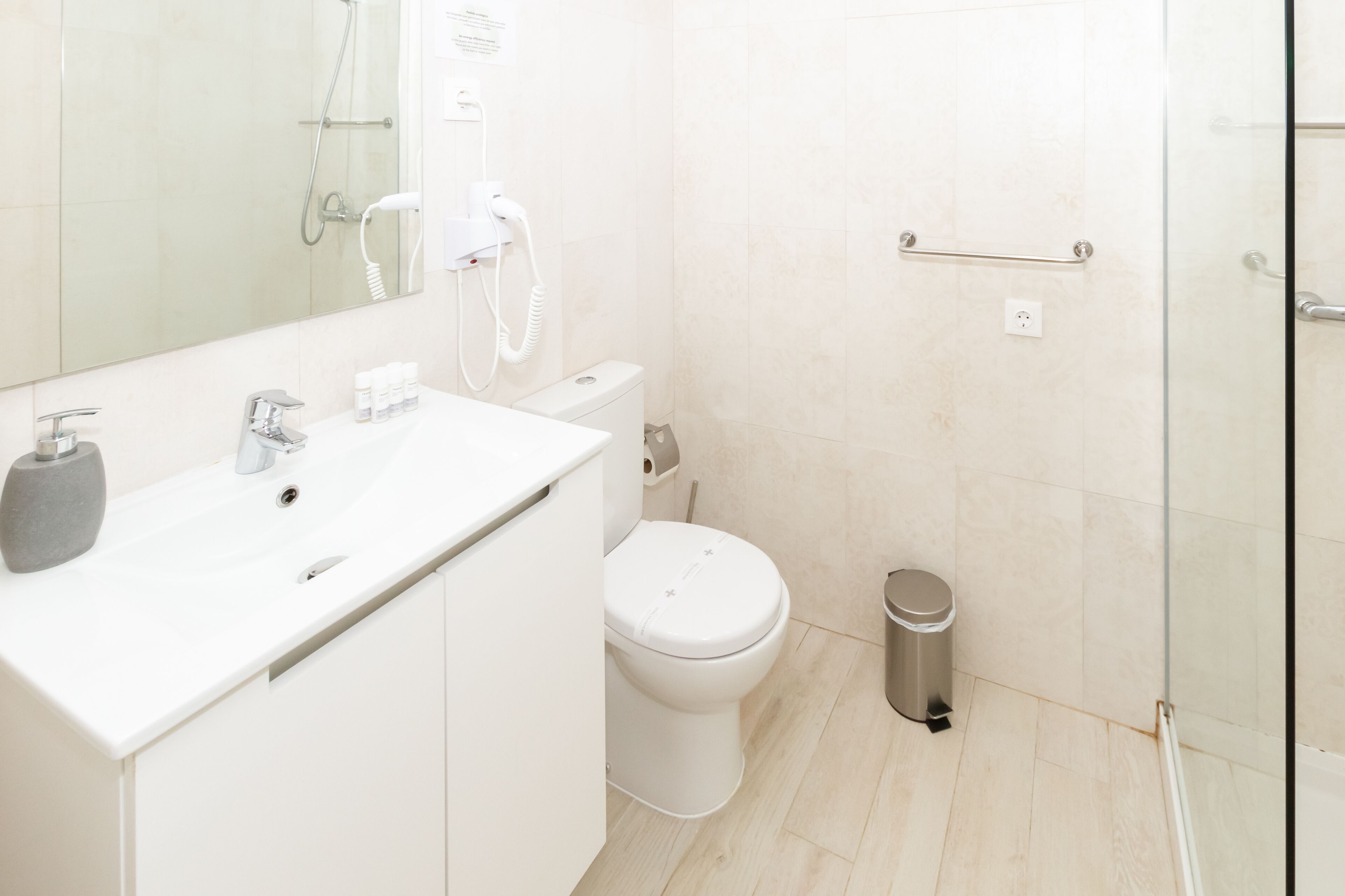 A modern bathroom with a white sink, toilet, and shower.