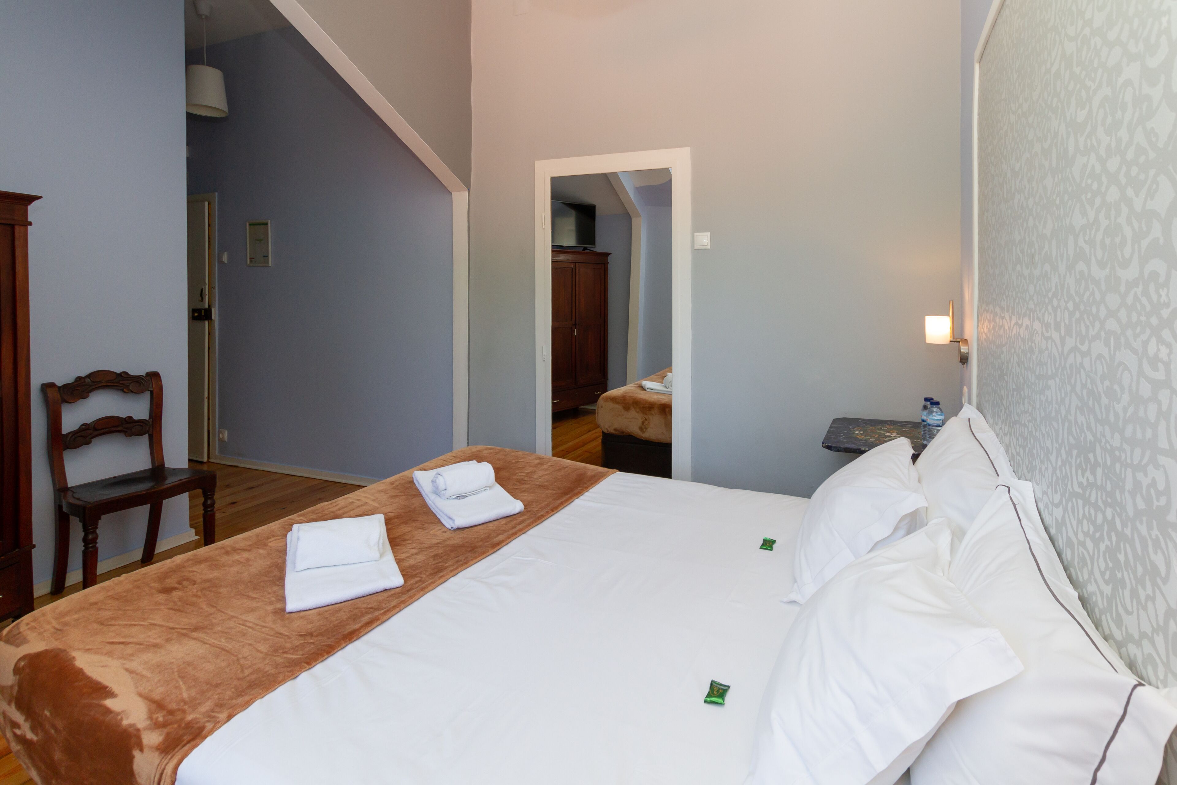 Une chambre d’hôtel avec un lit, une chaise, un bureau et une armoire.
