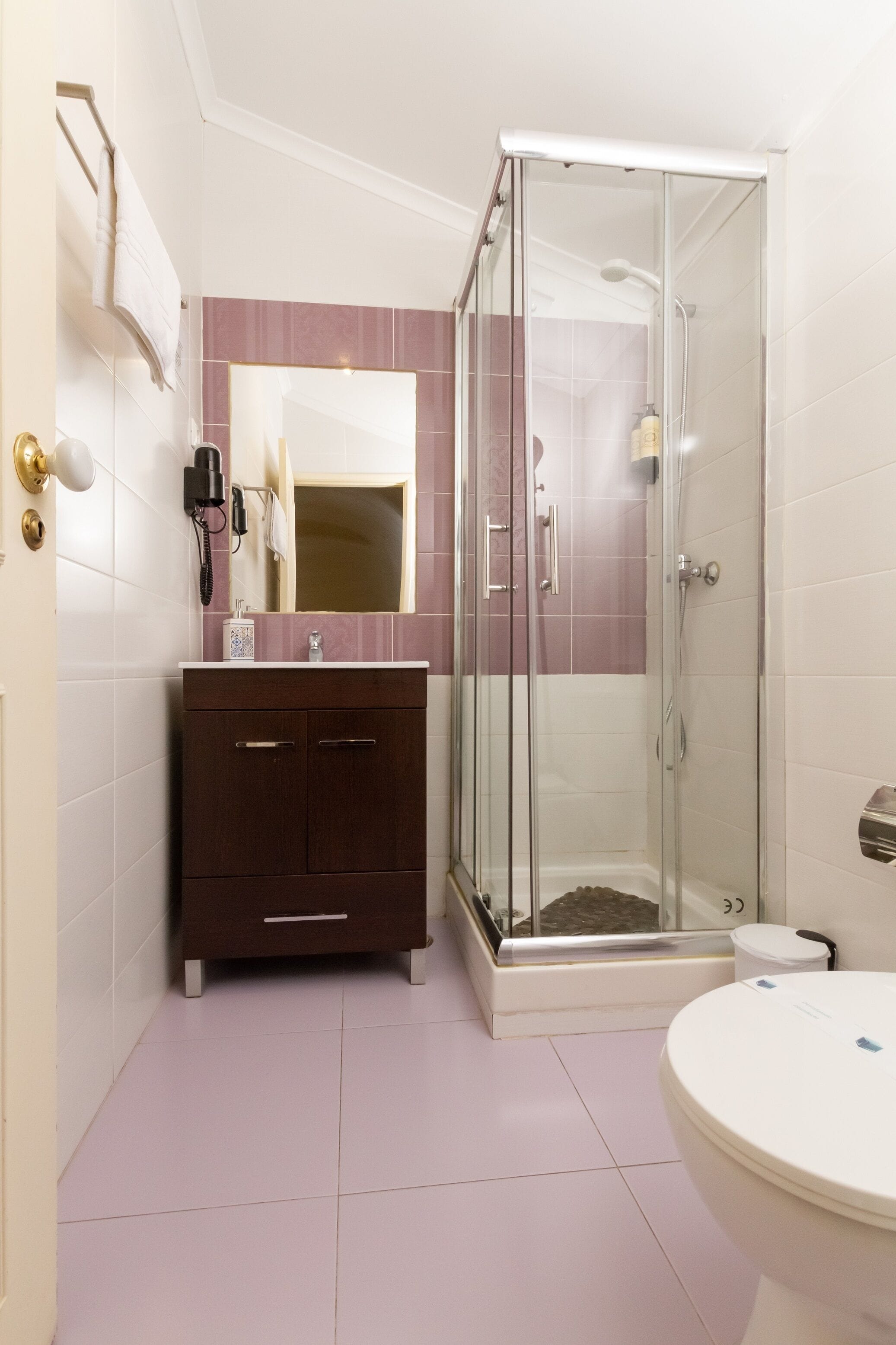 A bathroom with a glass-enclosed shower, a vanity with a mirror, and a toilet.
