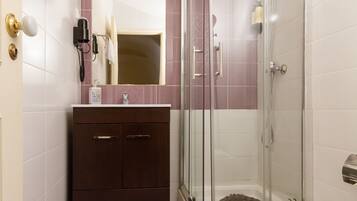 A bathroom with a glass-enclosed shower, a vanity with a mirror, and a toilet.
