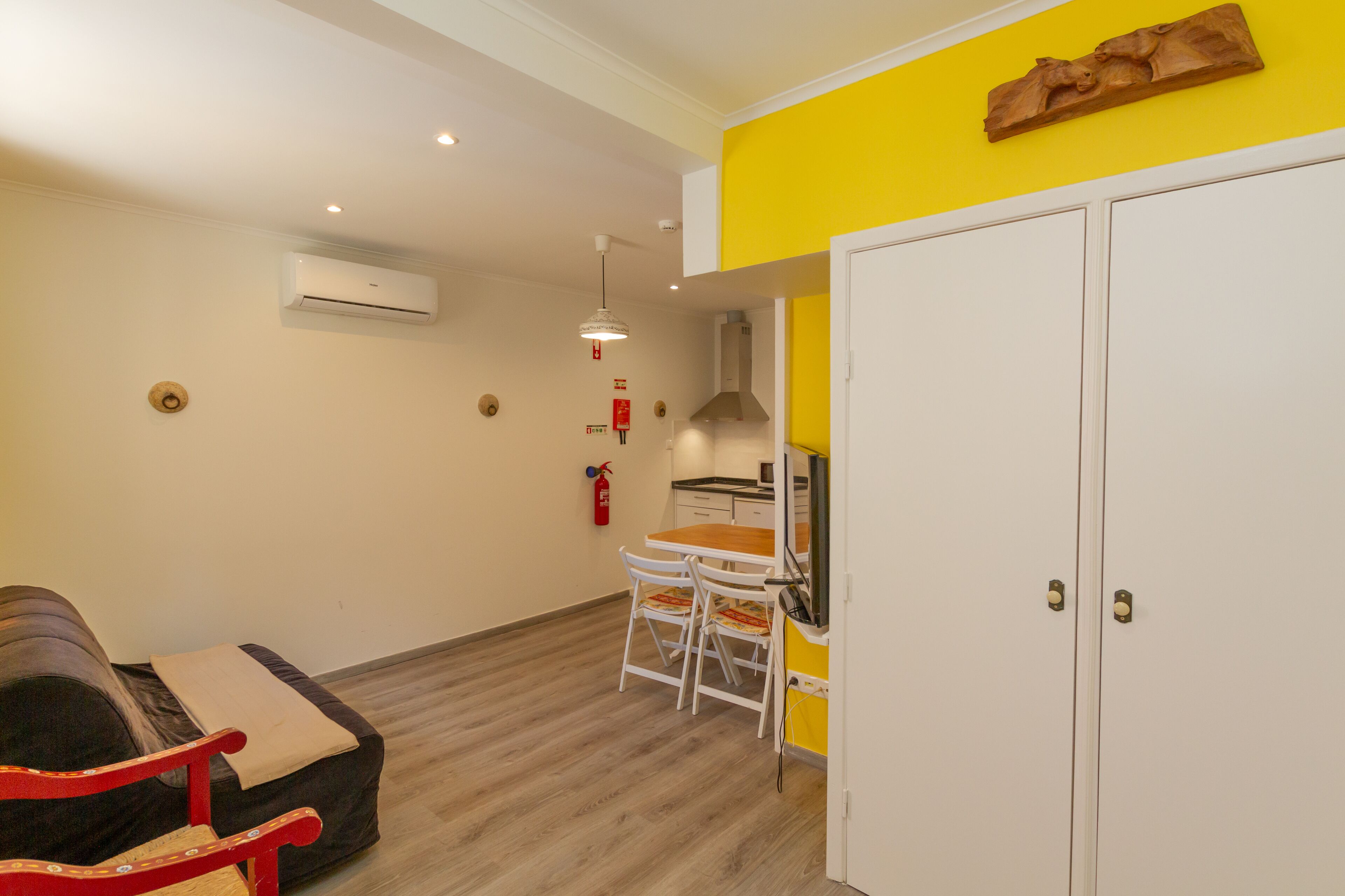 Un espacio habitable compacto con sofá, mesa de comedor y kitchenette.