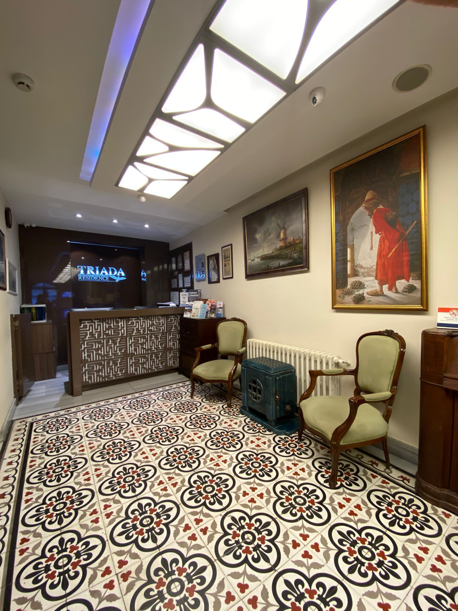 Un vestíbulo de hotel con piso estampado, un mostrador de recepción y un cuadro en la pared.