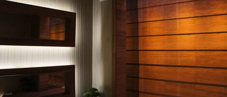 A modern bathroom with a wooden wall, a built-in sink, and a small potted plant.