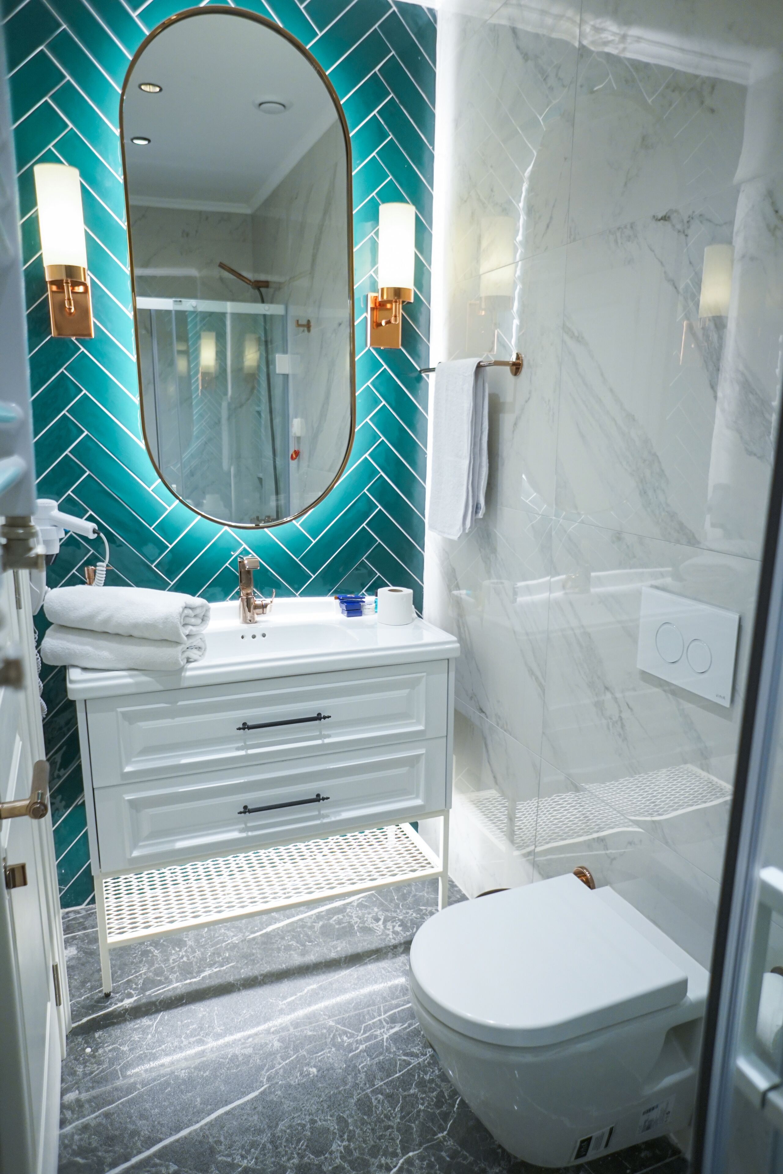 A bathroom with a white vanity, a large mirror, a sink, and a toilet.