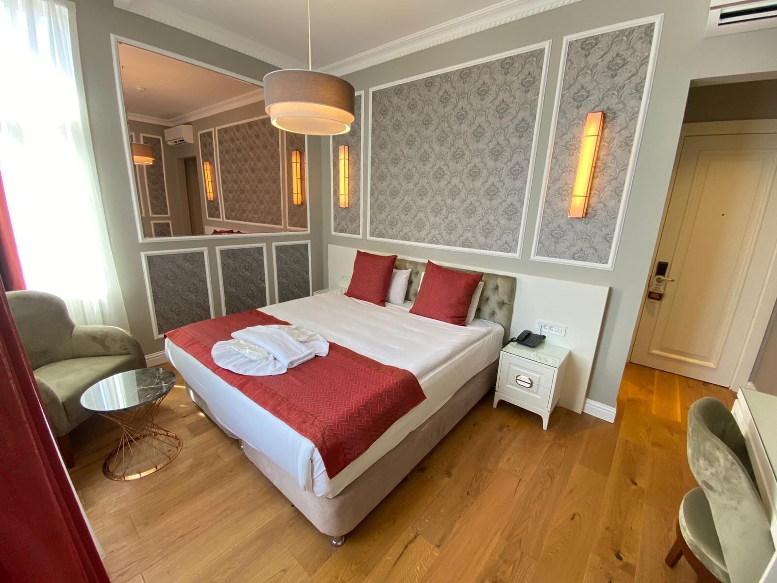 A hotel room with a large bed, a bedside table, a chair, and a small round table.