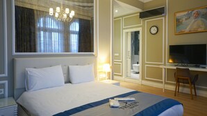A hotel room with a large bed, a desk, a television, and a clock on the wall. - Triada Hotel Taksim (Istanbul)