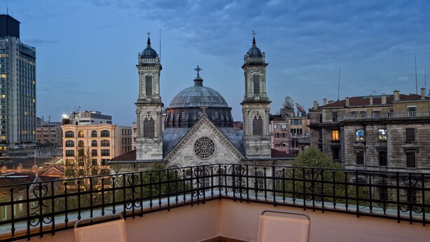 A terrace with a round table and four chairs, overlooking a historic building with two towers and a dome. - Triada Hotel Taksim (Istanbul)