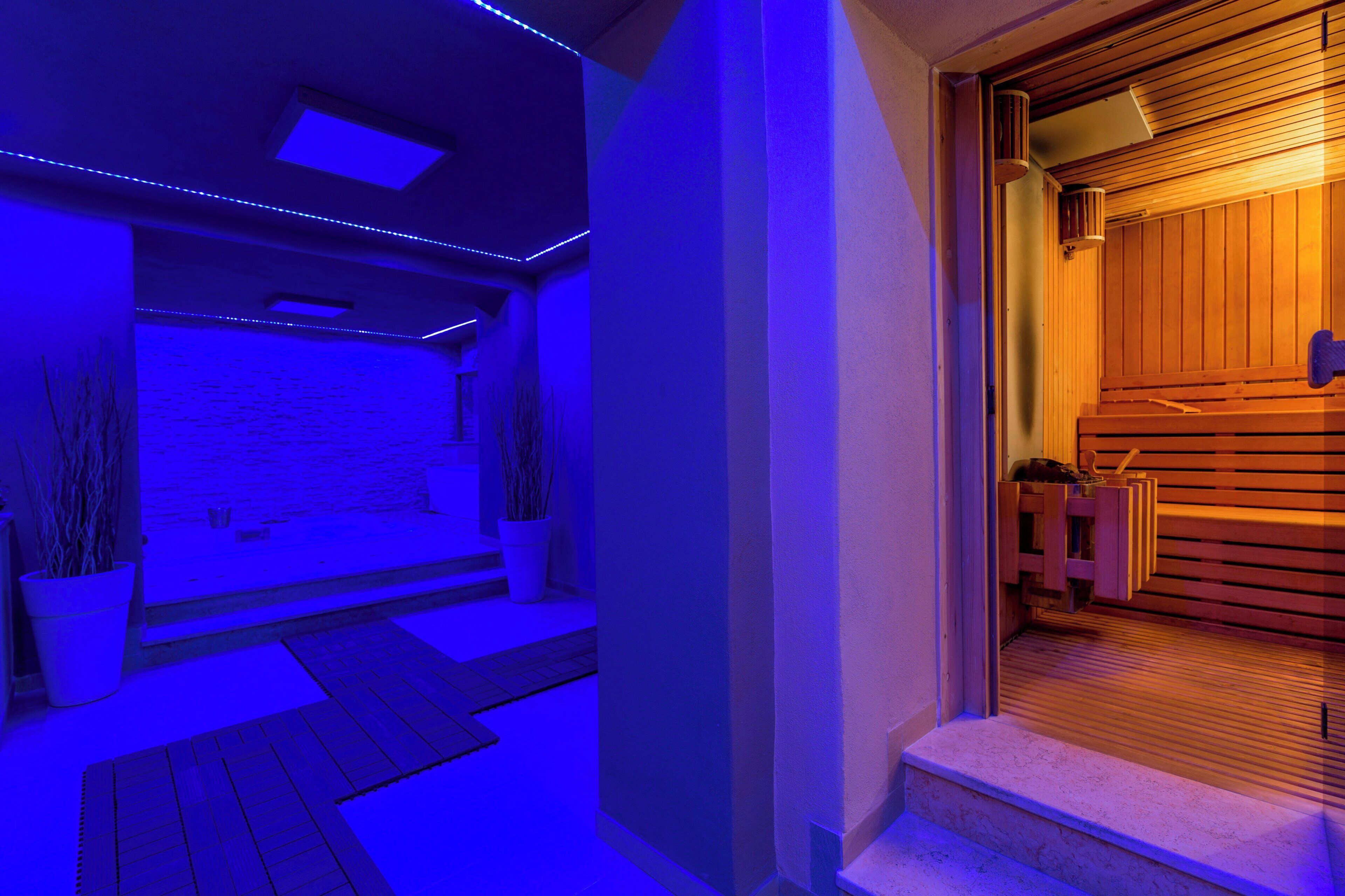A modern interior with a wooden staircase leading to a room, a wall-mounted heater, and a potted plant.