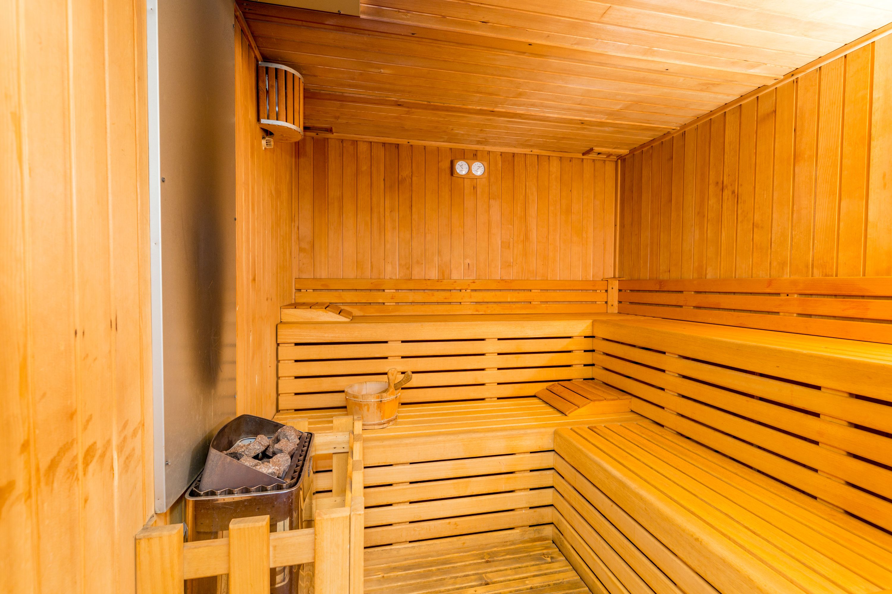 Una sauna de madera con bancos y un calentador pequeño.