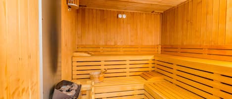 Una sauna de madera con bancos y un calentador pequeño.