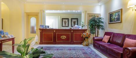 A reception area with a red leather sofa, a patterned rug, and a reception desk.