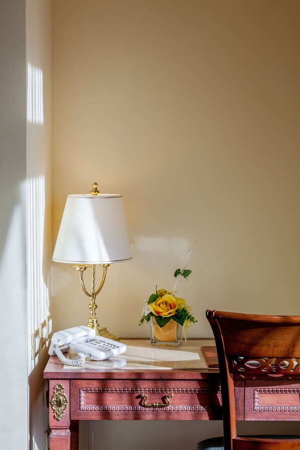 Un bureau en bois avec un téléphone, une lampe et un vase rempli de fleurs.