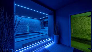 A modern spa area with a stone wall, a heated floor, and a glass partition.