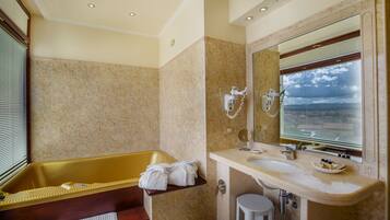 Une salle de bain avec une baignoire, deux lavabos et un grand miroir.