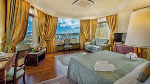 Habitación de hotel con cama, escritorio, silla, televisor y vista a la ciudad.