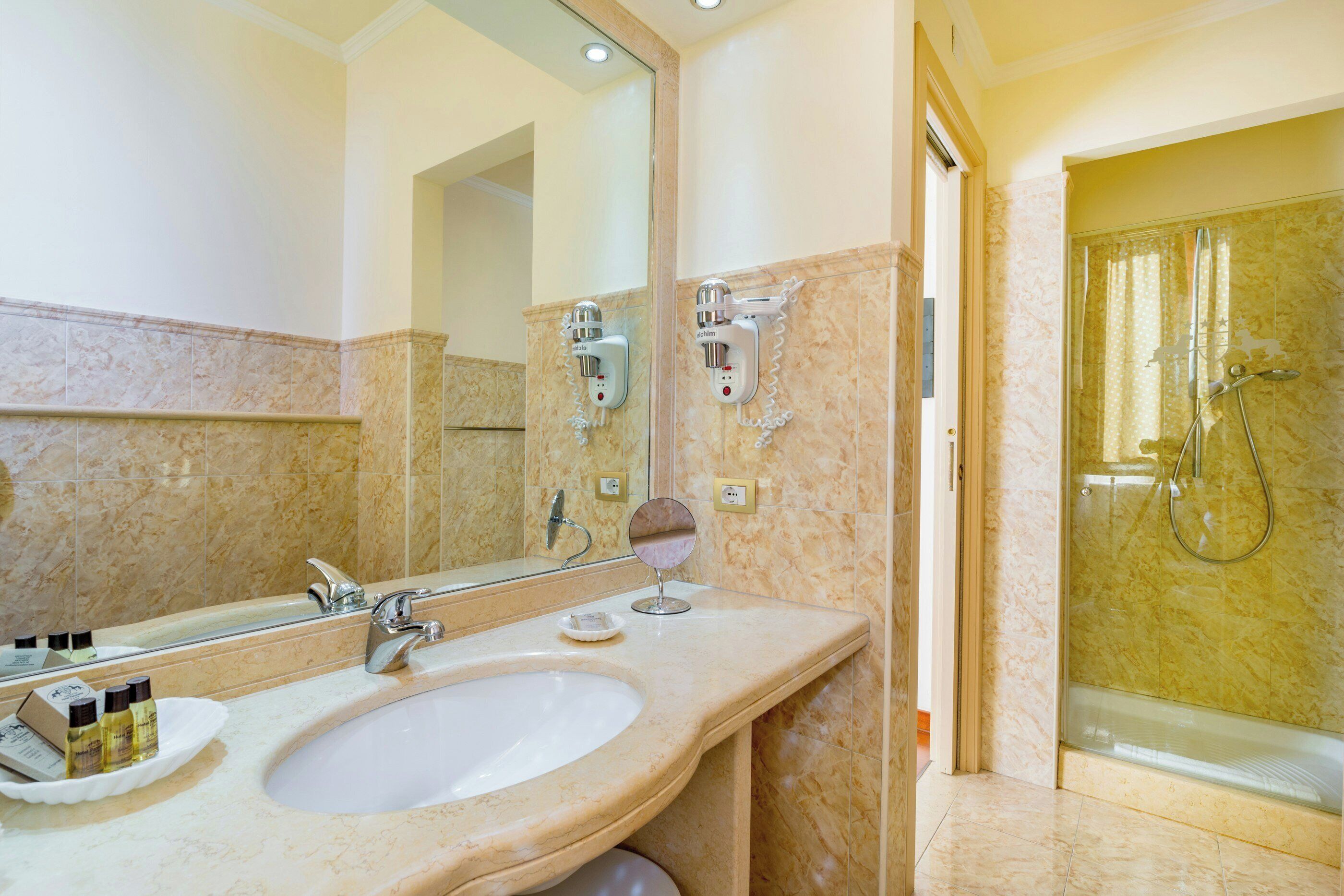 A bathroom with a sink, mirror, and shower.