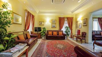 A living room with a brown leather sofa, a red patterned rug, and a television.