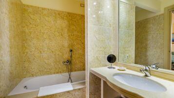 Une salle de bain avec une baignoire, un lavabo, un miroir et une douche.