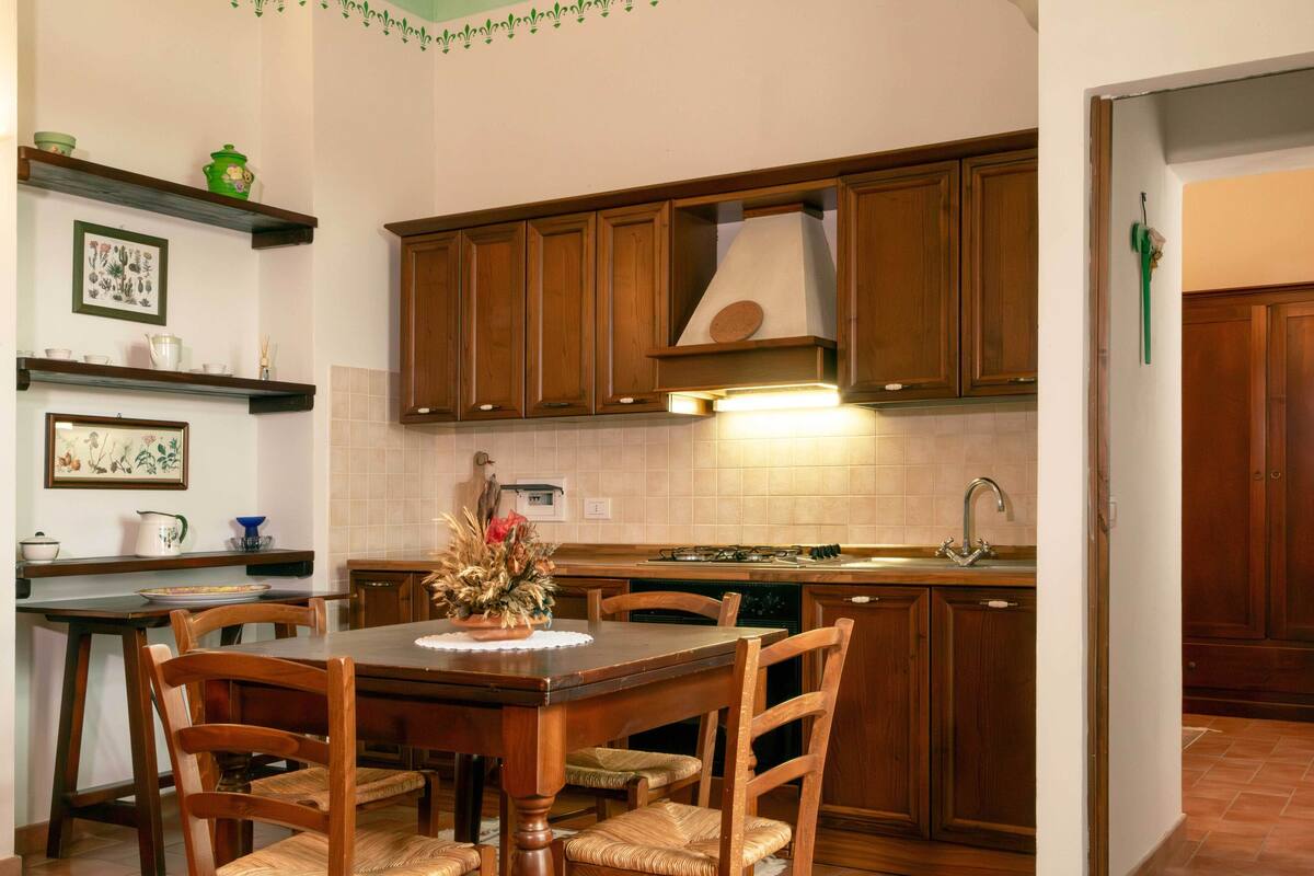 Una cocina con armarios de madera, una mesa de comedor con sillas y un salpicadero de azulejos.