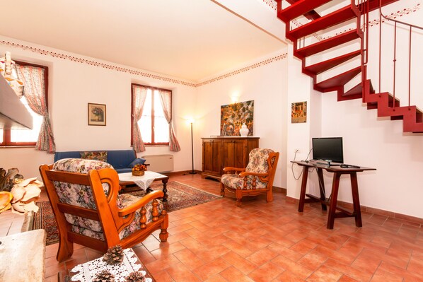A living room with a sofa, two chairs, a coffee table, a TV stand, and a red spiral staircase.