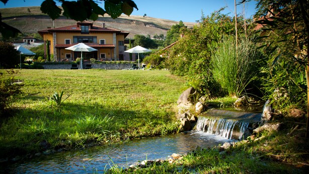 A house with a garden, a small stream, and outdoor seating. - La Lluriga (Llanes)