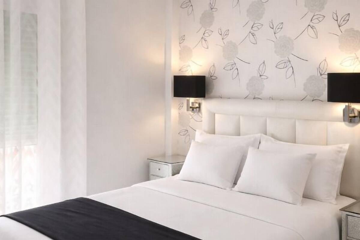Un dormitorio moderno con una cama grande, dos mesitas de noche y lámparas de pared.