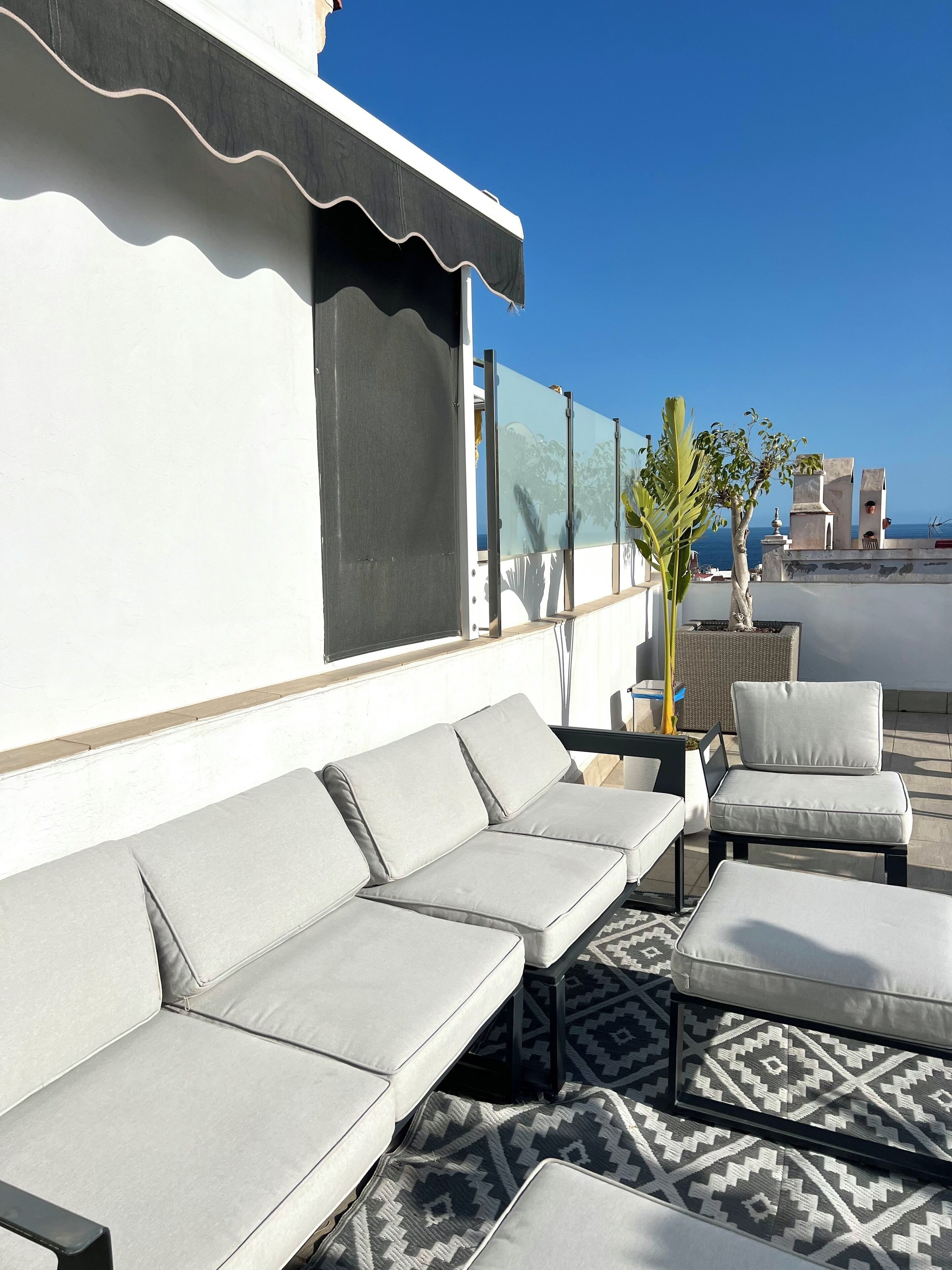 Terraza en la azotea con un conjunto de sofás, una silla y un tapete estampado.