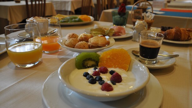 A breakfast setting with various dishes, including a bowl of yogurt with fruits, orange juice, and coffee. - Saint Pierre (Saint-Pierre)