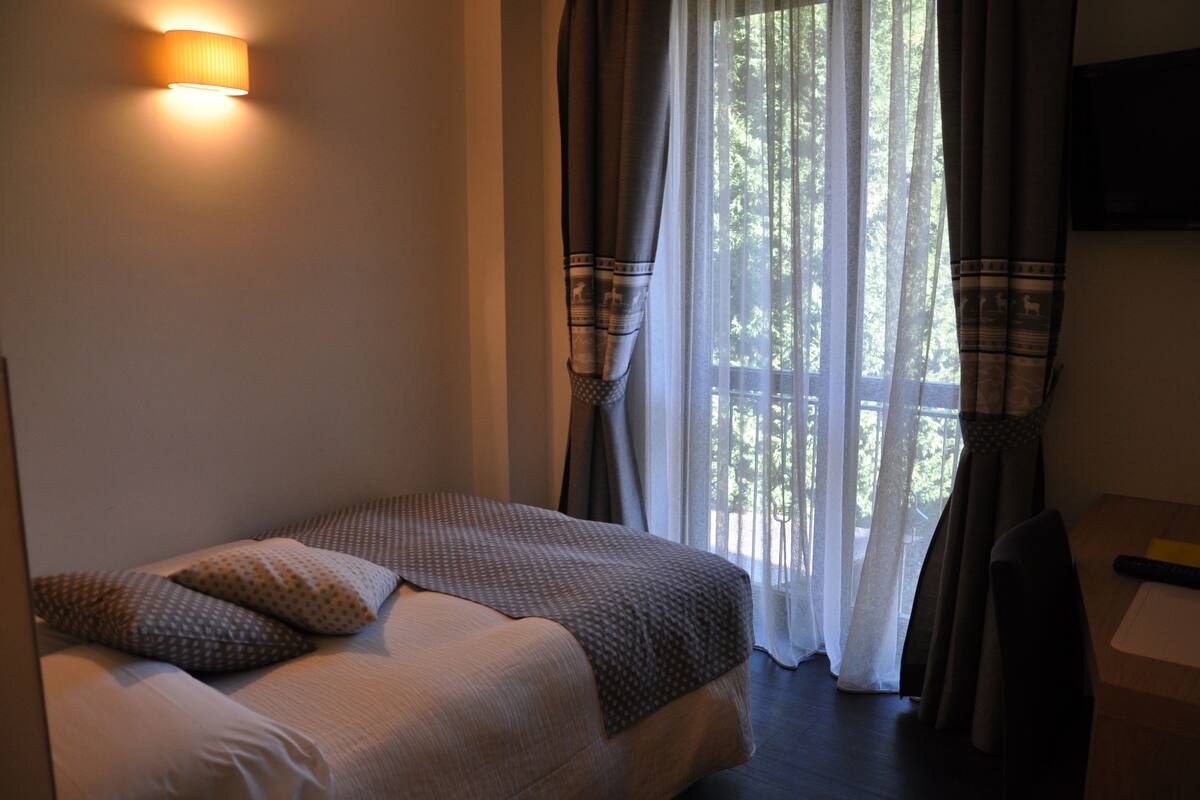 Ein Hotelzimmer mit Bett, Schreibtisch und einem Fenster mit Vorhängen.
