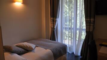 Una habitación de hotel con cama, escritorio y ventana con cortinas.