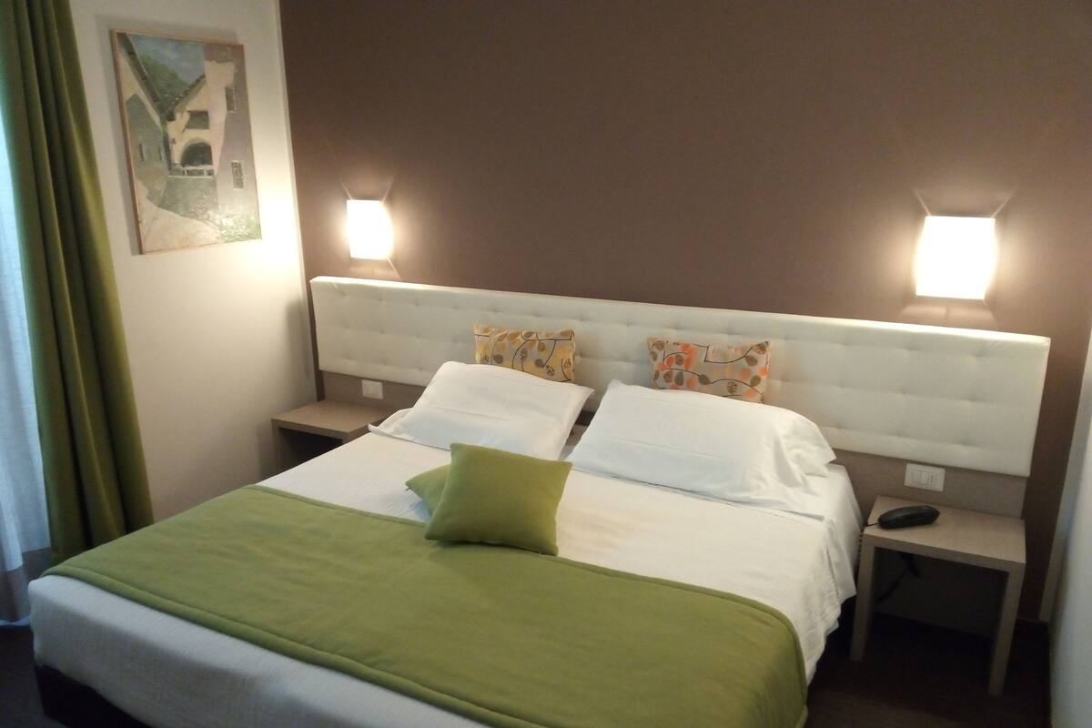 Ein Hotelzimmer mit einem großen Bett, zwei Nachttischen und zwei Wandleuchten.