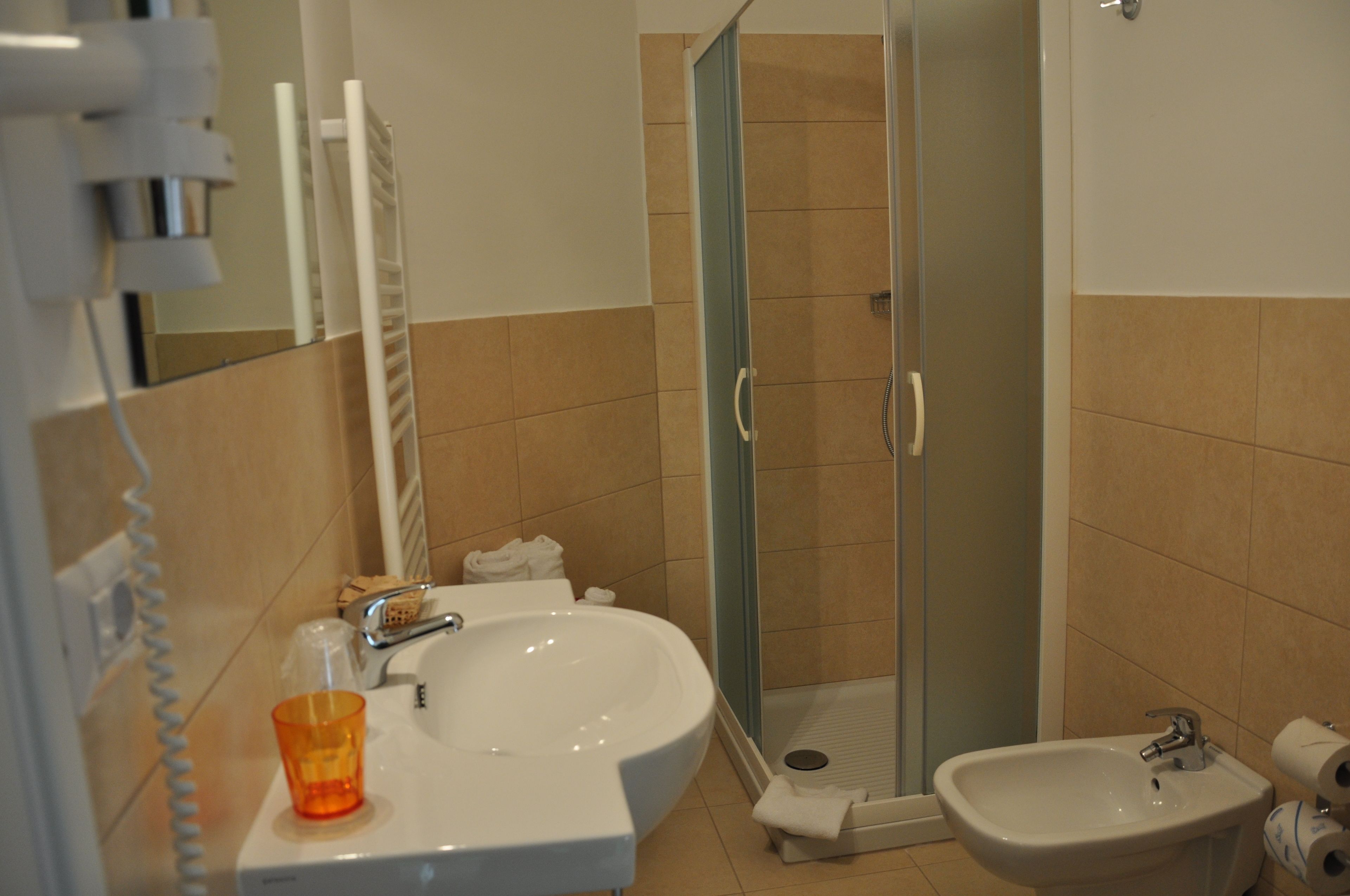 Un baño con lavamanos, bidé y ducha con mampara de vidrio.