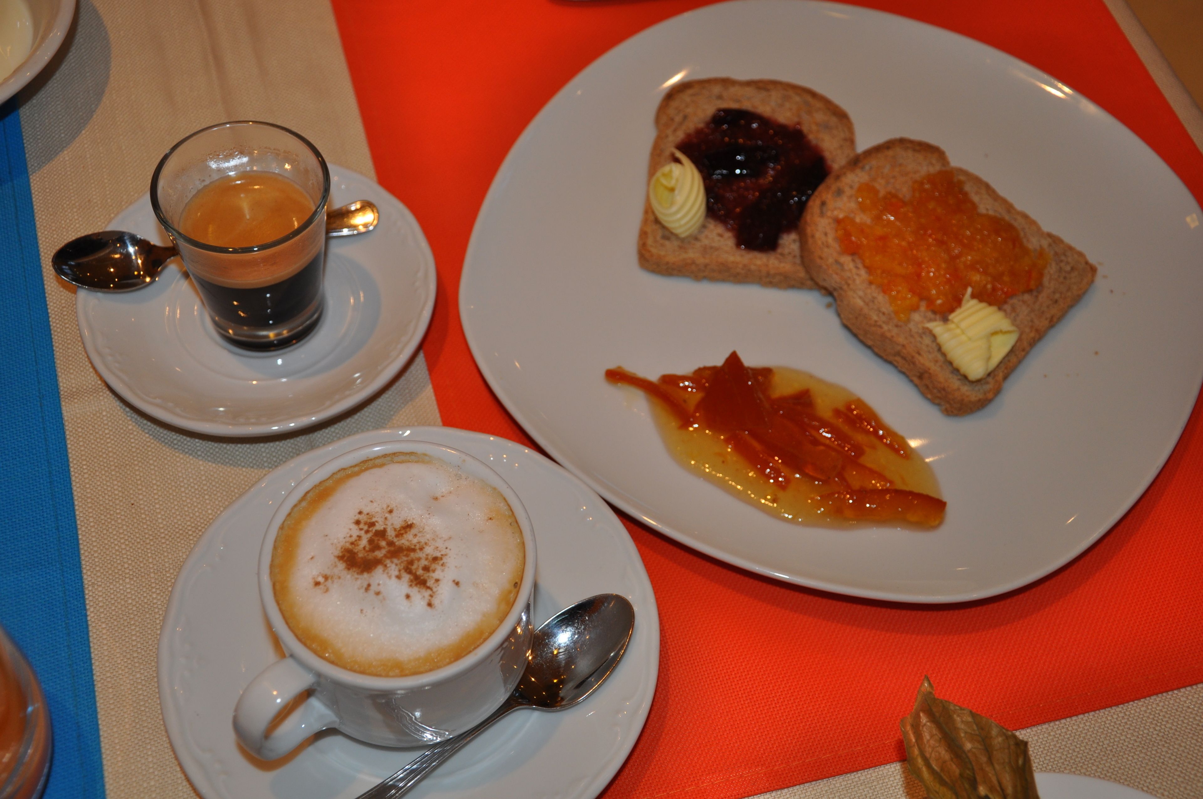 Un desayuno con una taza de café, una tostada con mermelada y una porción de tocino y fruta.