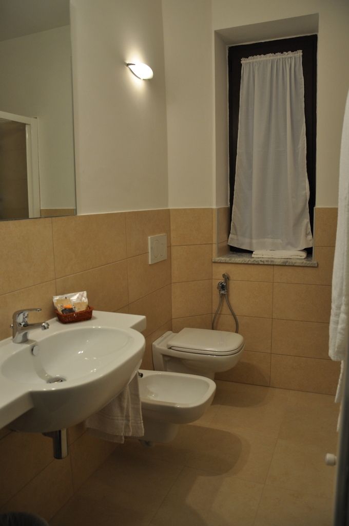 A bathroom with a sink, toilet, and a window with a curtain.