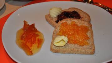 A plate with toast and jam, and a side of fruit.