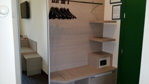 A modern hotel room with a walk-in closet, built-in shelves, and a small seating area. - Saint Pierre (Saint-Pierre)