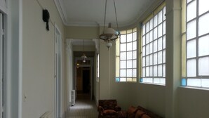 A hallway leading to a living room with a sofa, a glass coffee table, and large windows with blinds. - New Arapey Hotel (Montevideo)