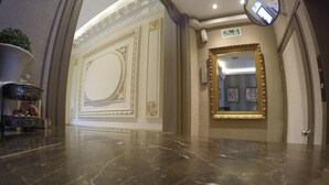 A polished marble lobby with ornate wall decorations and a large mirror. - New Arapey Hotel (Montevideo)