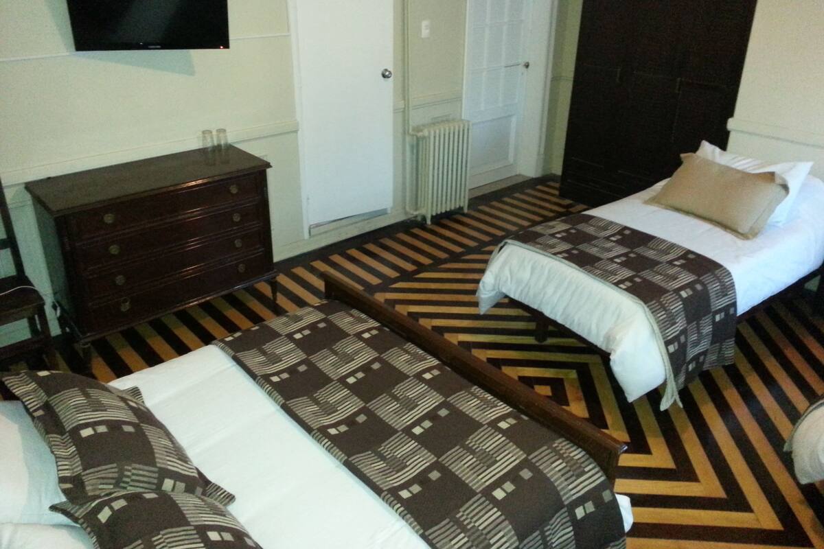 Una habitación de hotel con dos camas, un aparador, un televisor y una puerta.