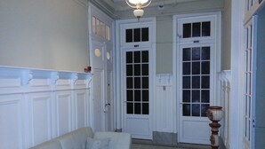 A hallway with a white sofa, two doors, and a patterned floor. - New Arapey Hotel (Montevideo)