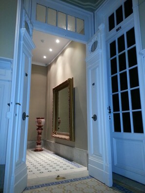 A hallway with a large mirror, a decorative vase, and a patterned floor. - New Arapey Hotel (Montevideo)