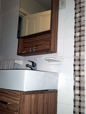 A bathroom with a white sink, wooden cabinet, and a mirror above it. - New Arapey Hotel (Montevideo)
