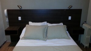 A hotel room with a large bed, two bedside tables, a headboard, and a wall-mounted telephone. - New Arapey Hotel (Montevideo)