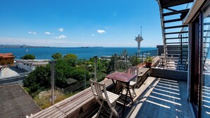 Un balcón con vista al mar, una torre y un paisaje urbano.