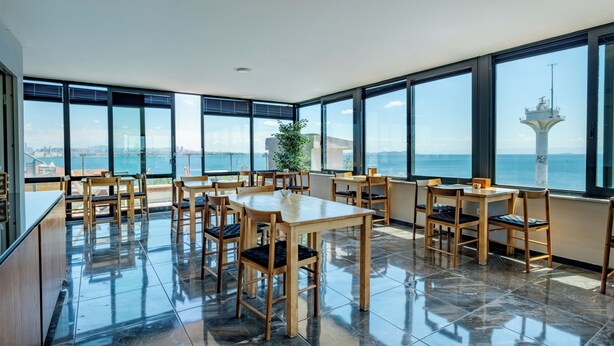 Un comedor amplio con ventanas grandes que ofrecen vista al mar y un faro.